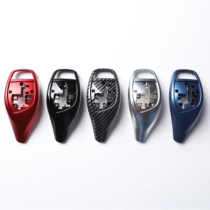 Caches de levier de vitesse BMW présentés en rouge, noir, carbone, argent et bleu