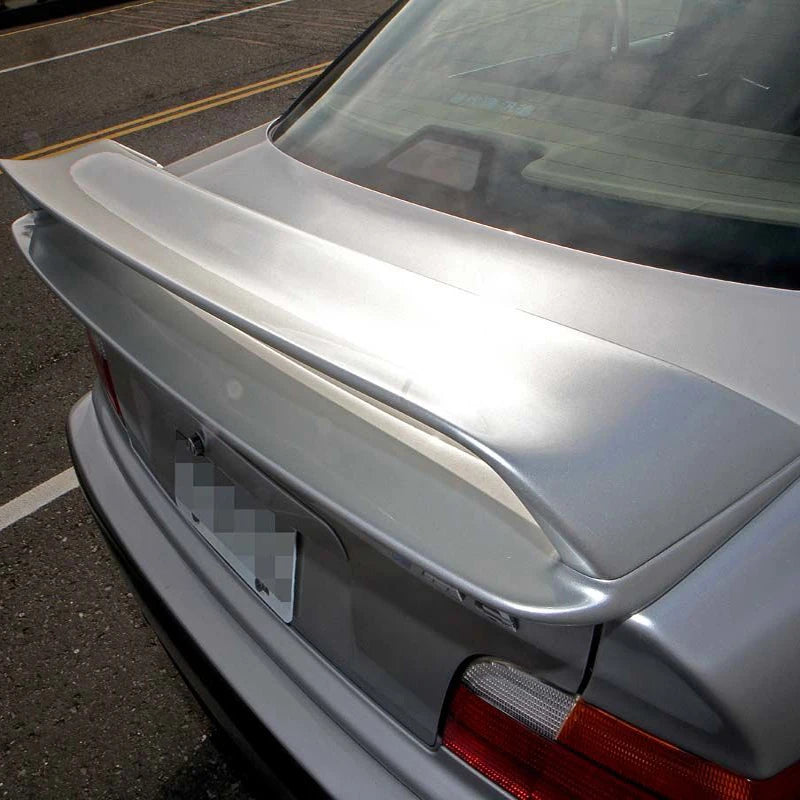 Becquet arrière BMW Série 3 E36 coupé style M3 GT en blanc monté sur le coffre d’une voiture grise