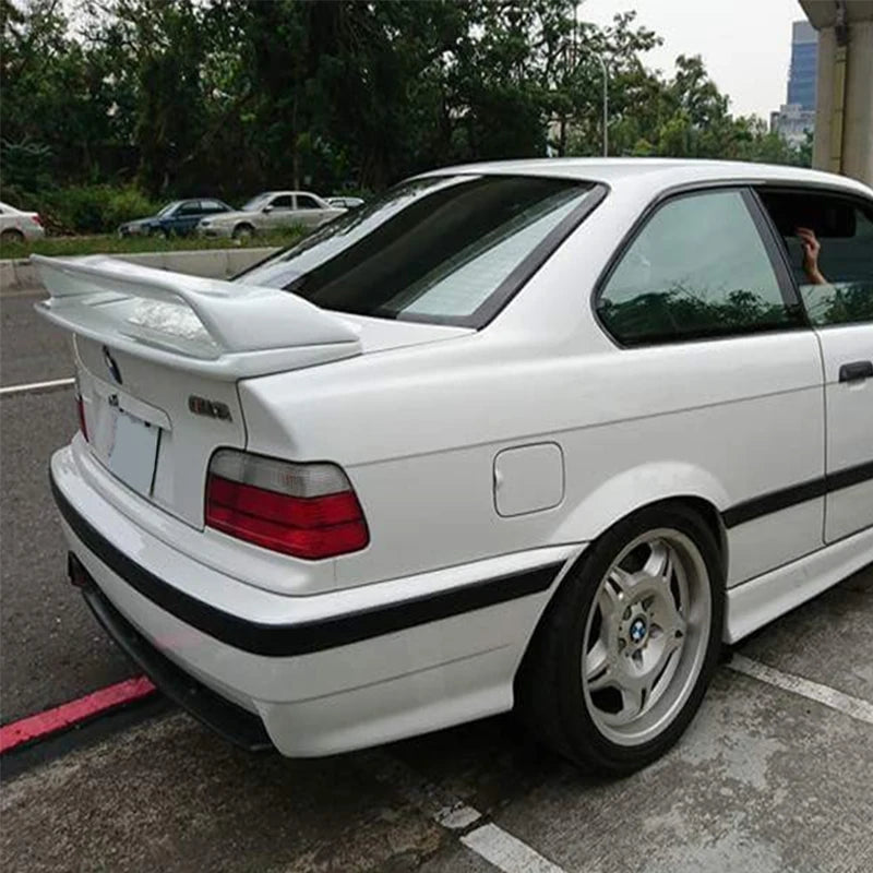 Vue arrière d’une BMW Série 3 E36 coupé blanche équipée d’un becquet style M3 GT