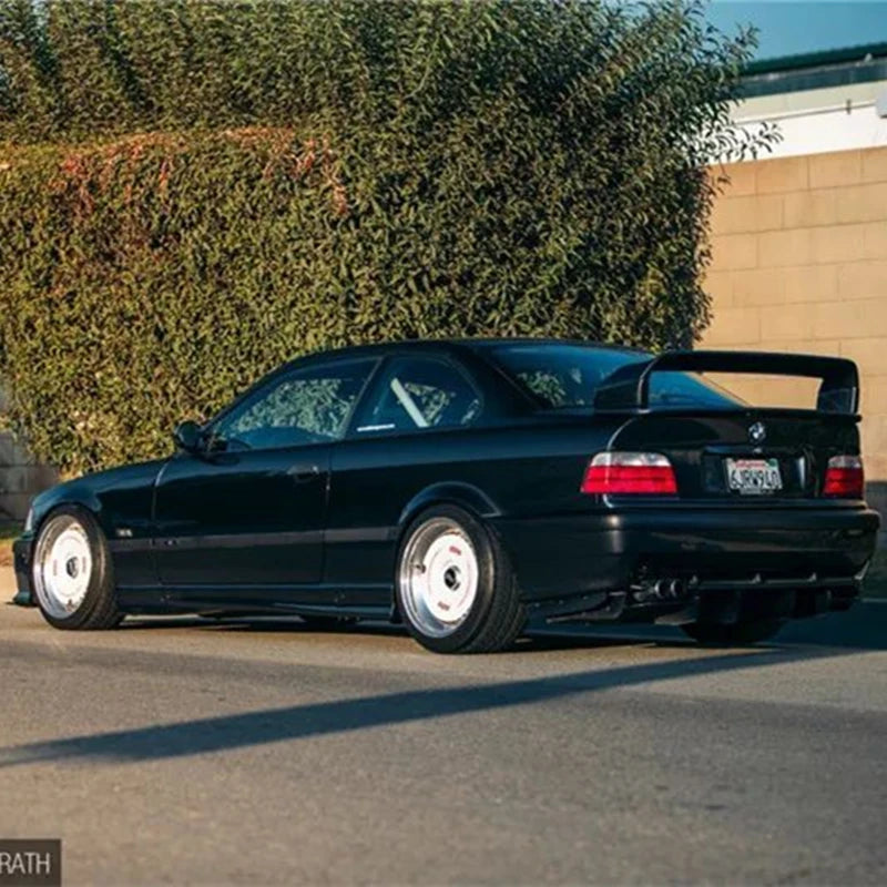 Vue arrière d’une BMW Série 3 E36 coupé noire équipée d’un becquet style M3 GT