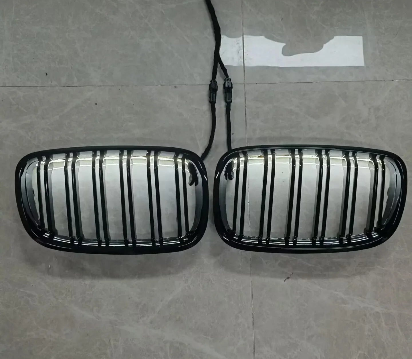 Paire de calandres BMW noir brillant vue de face sur fond gris