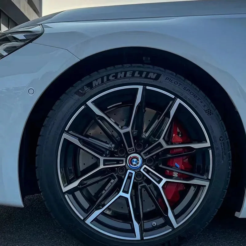 Stickers logo M montés sur étriers rouges visibles derrière une jante noire BMW