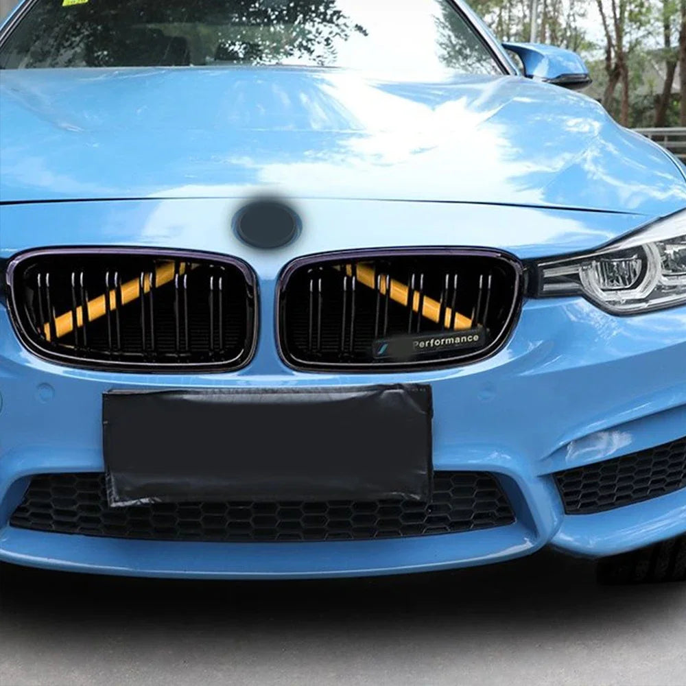 Bandes de calandre BMW installées sur une calandre noire avec rendu sur voiture bleue