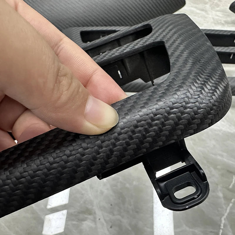 Détail du contour d’autoradio BMW en finition carbone mat tenu en main